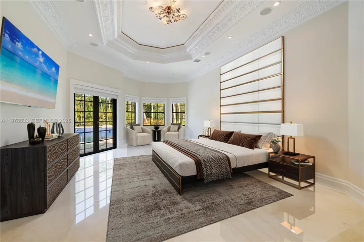 Spacious primary suite with soring ceilings, abundant natural light and serene views of the pool.