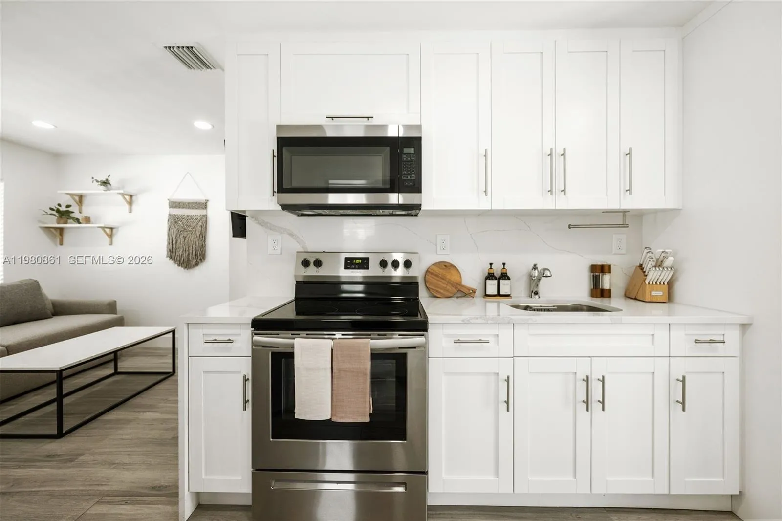 Designer kitchen showcasing crisp white shaker cabinetry, quartz countertops, and stainless-steel appliances seamlessly integrated into an open-concept layout. Thoughtfully styled with refined finishes, warm wood accents, and modern lighting, this elegant culinary space blends timeless sophistication with everyday functionality—perfect for both entertaining and elevated daily living.
