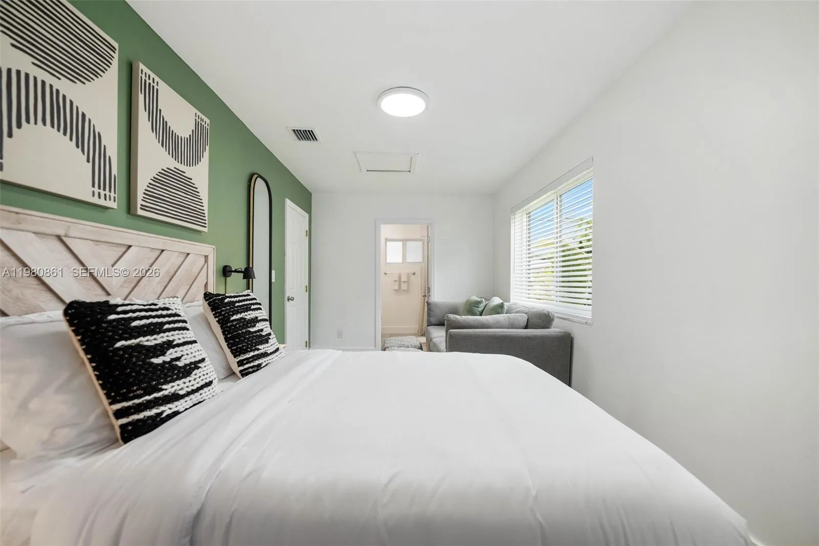 #1. Spacious and serene bedroom suite featuring a designer accent wall, custom wood headboard, and a thoughtfully integrated sitting area—bathed in natural light and designed for elevated comfort, versatility, and timeless luxury living