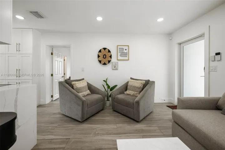 Sophisticated living area designed with balance and elegance, featuring wide-plank flooring, recessed lighting, and a refined neutral palette. Plush seating, curated wall art, and clean architectural lines create a serene, gallery-inspired setting that feels both inviting and elevated—perfect for relaxed living or intimate entertaining.