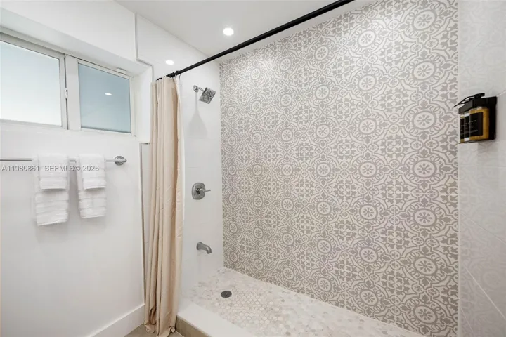 to Master Bedroom with striking spa-inspired shower featuring designer patterned tile, refined fixtures, and a serene, light-filled ambiance—delivering a sophisticated, resort-quality bathing experience.
