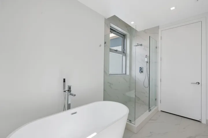 primary suite tub and shower with door entrance to private toilet