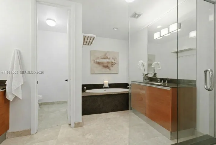 spacious spalike bathroom with tub, water closet, and glass shower doors