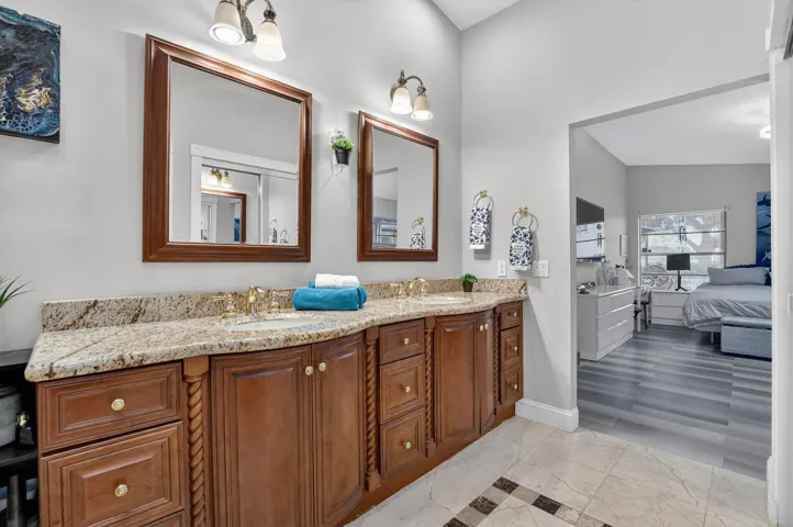 Extended, counter height vanity has a granite countertop and undermount sinks.