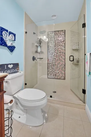 Guest bath shines with a frameless shower with porcelain tile and pretty inlays.