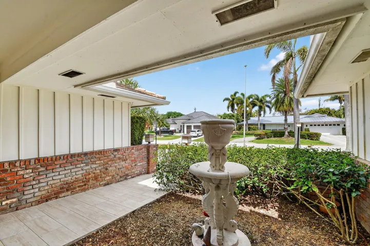 Covered front entry walkway featuring landscaped garden area and tiled approach to the main entrance.