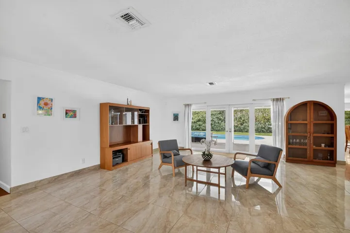 Spacious living room with tile flooring, built-in shelving, and large windows providing natural light.
