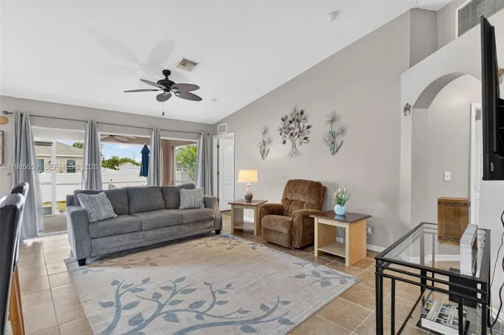 Spacious living area with vaulted ceiling and triple sliding glass doors to enclosed patio