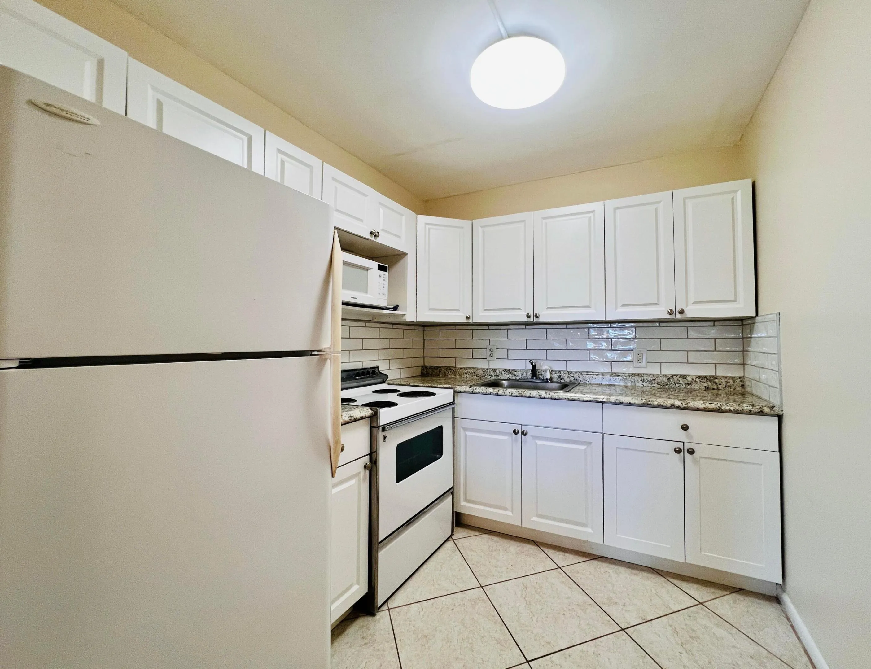 Pretty Updated Kitchen Featuring Crisp White Cabinets, Grante Look Counters, and Modern Subway Tile Backsplash