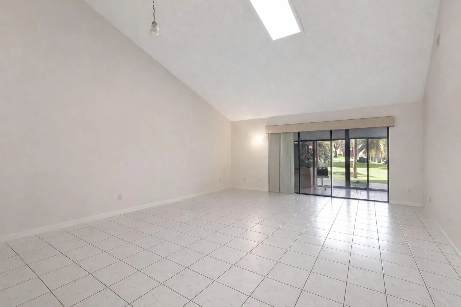 Open tiled space with vaulted ceilings & patio access.