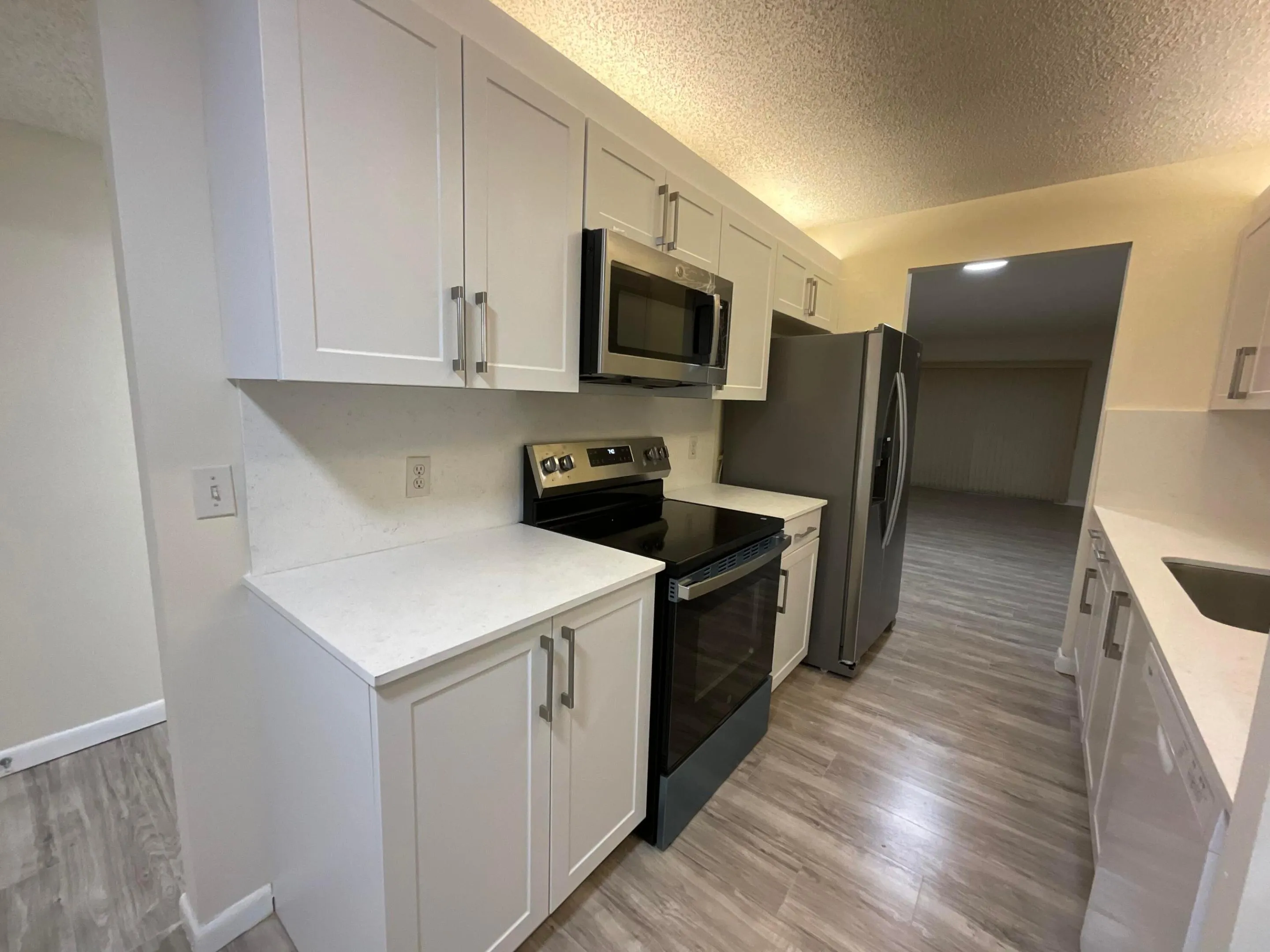 Stunning new kitchen with shaker cabinetry, quartz countertops & backsplash, new sink, faucet, flat cooktop stove/oven and microwave and a newer dishwasher and refrigerator.
