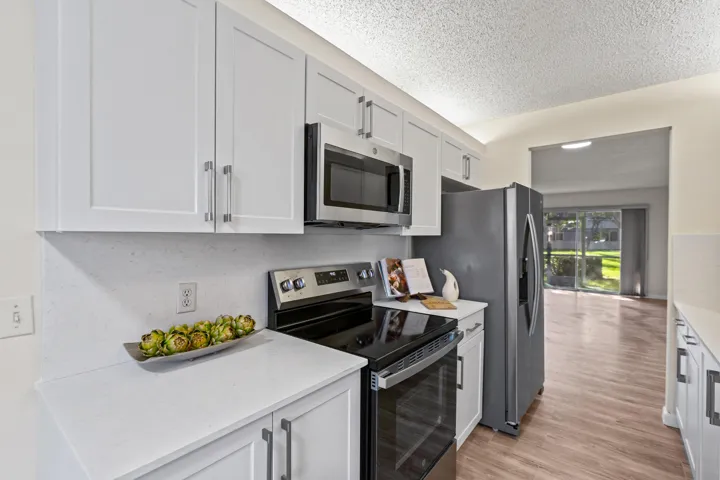 Stunning new kitchen with shaker cabinetry, quartz countertops & backsplash, new sink, faucet, flat cooktop stove/oven and microwave and a newer dishwasher and refrigerator.