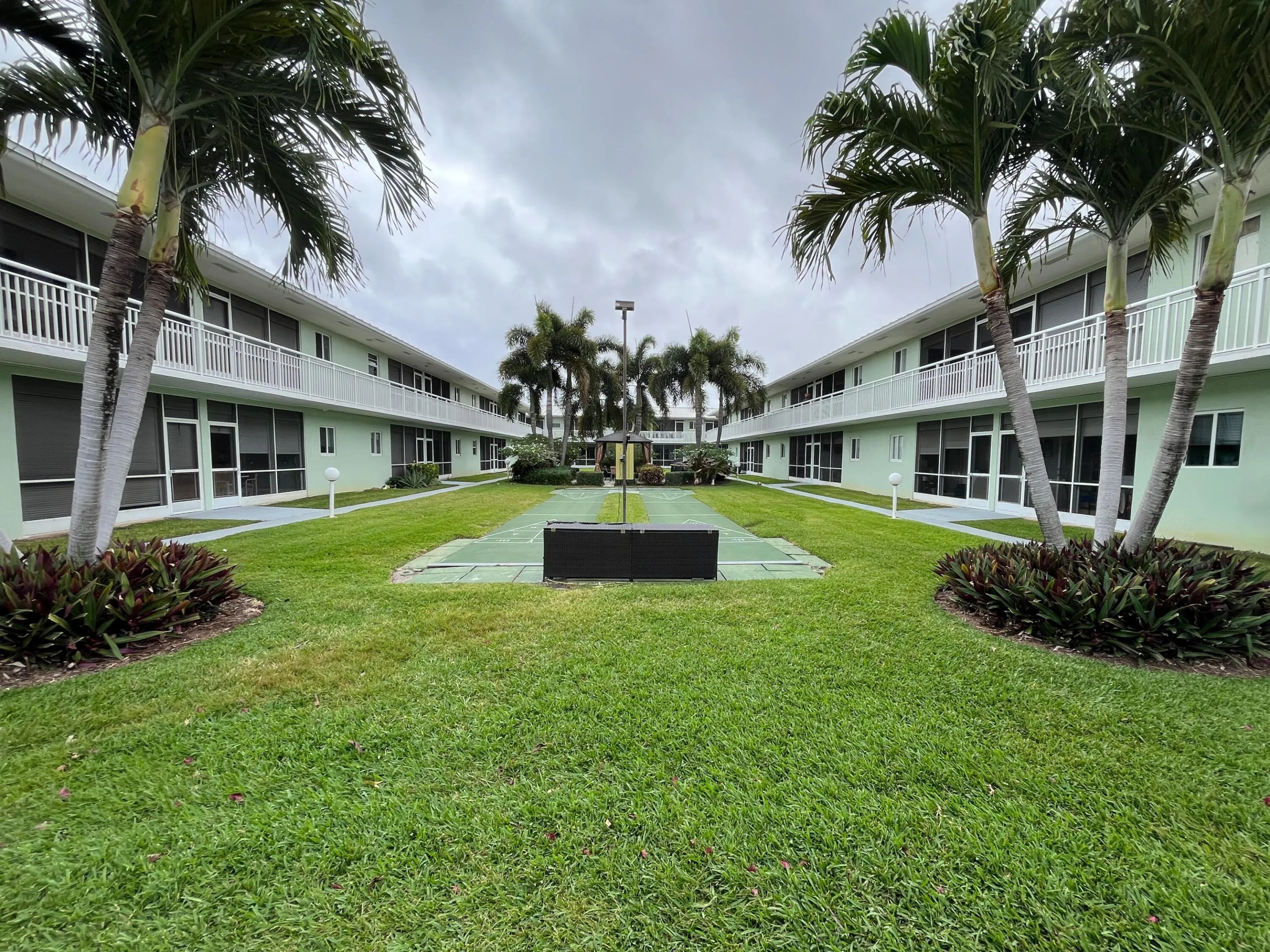 Another view of the courtyard which includes the heated pool, shuffleboard, grill and shaded sitting areas.