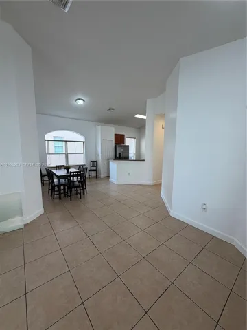 This is a photo that shows the dining area and kichen. The foreground shows thespace between the front door and dining room/kitchen area.
