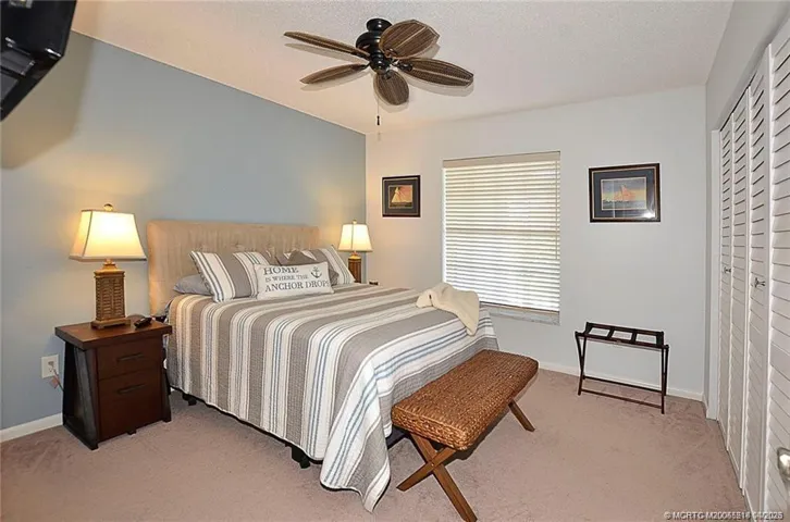 The inviting guest bedroom offers a relaxing retreat for family and visitors, featuring soft natural light, a ceiling fan, and plenty of space for comfortable accommodations.