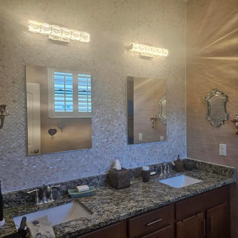 Master bathroom double sinks double medicine mirrored cabinets tile wall custom light fixtures.