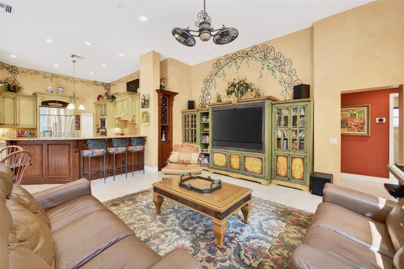 Family Room / Great room w/ volume ceilings and custom painted walls and beautiful fan, Two custom wood cabinets are built in and hand painted. Built in TV and sound bar to stay, plus wine storage cabinet. To the right are two bedrooms and a hallway guest bathroom Family Room / Great room w/ volume ceilings and custom painted walls and beautiful fan, Two custom wood cabinets are built in and hand painted. Built in TV and sound bar to stay, plus wine storage cabinet. To the right are two bedrooms and a hallway guest bathroom