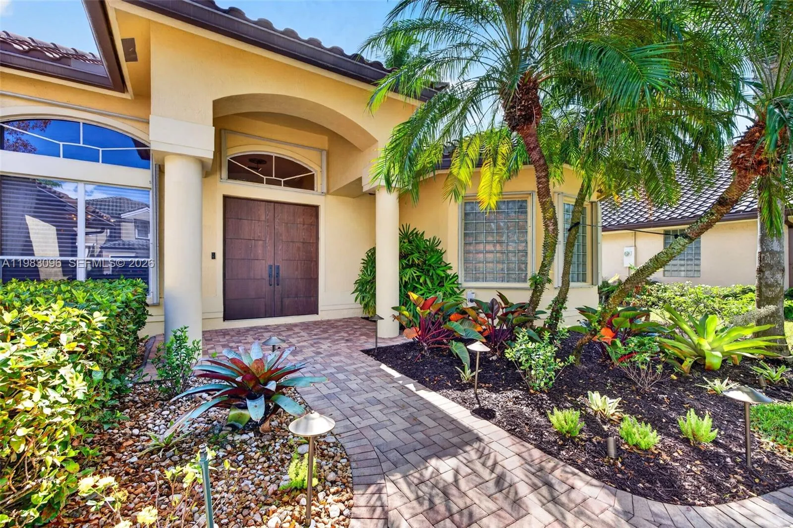 Impact rated front doors and covered entrance with beautiful architecture and pavered driveway and landscape lighting Impact rated front doors and covered entrance with beautiful architecture and pavered driveway and landscape lighting