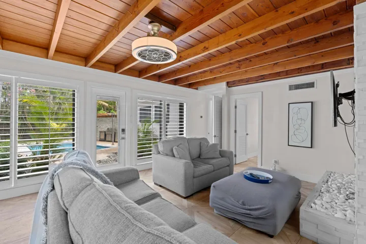 Living room with floor to ceiling windows overlooking the backyard and pool.