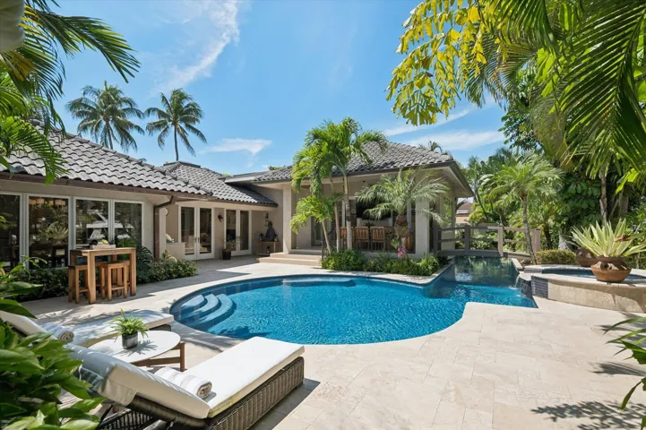 This backyard oasis includes a summer kitchen, outdoor dining area, heated/chilled saltwater pool with lap lane, waterfall spa, and private dock entrance.