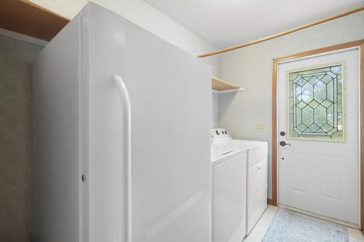 Utility room with washer,dryer, freezer,and exterior access.