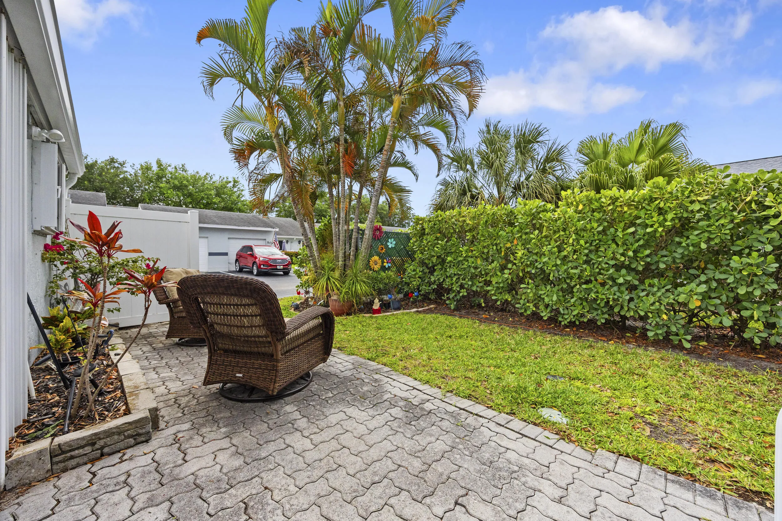 Charming outdoor patio space featuring a paver deck, perfect for relaxing or entertaining. Surrounded by lush tropical landscaping and privacy fencing, this inviting backyard offers a peaceful setting with plenty of room for outdoor seating, grilling, and enjoying the South Florida lifestyle.