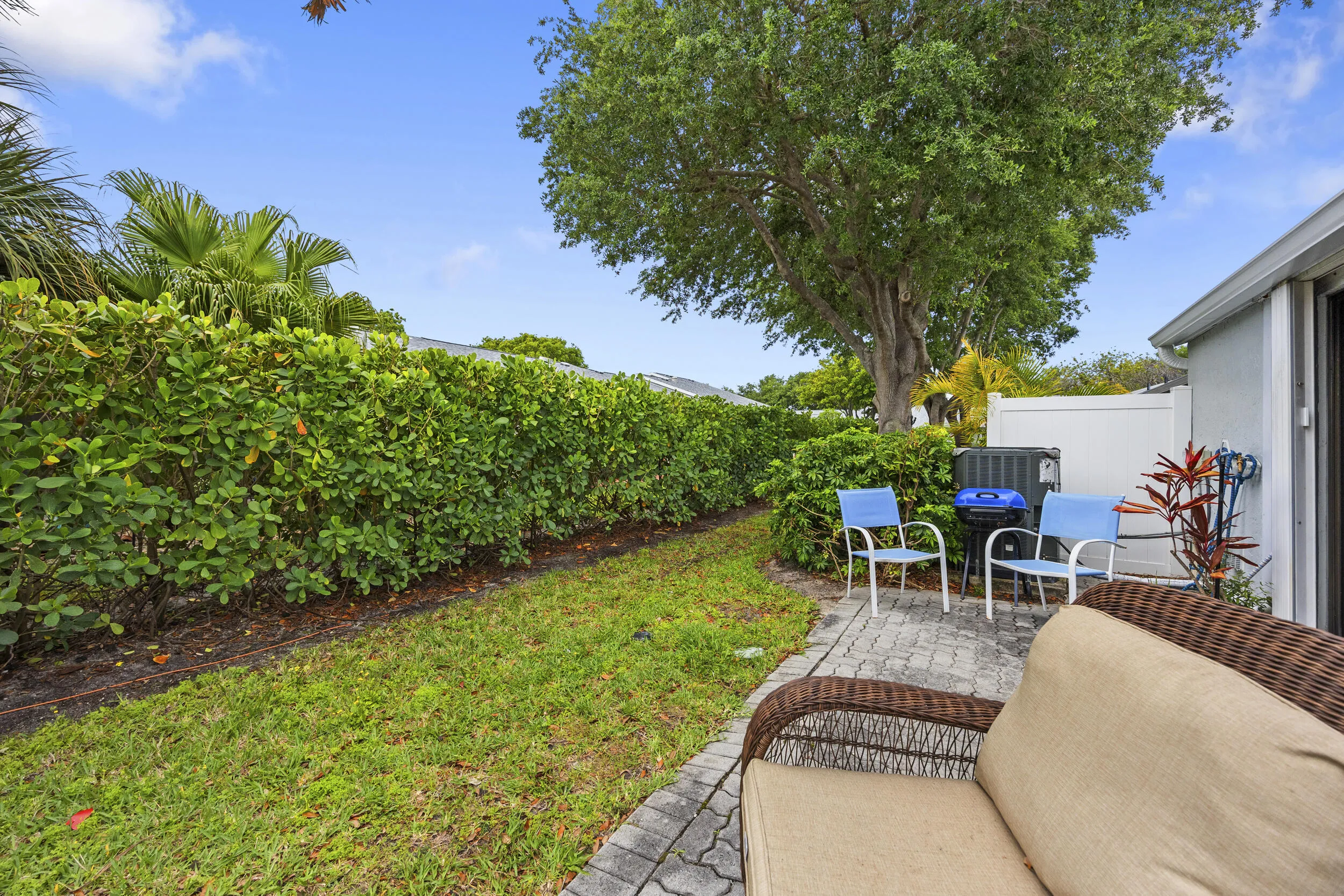 Charming outdoor patio space featuring a paver deck, perfect for relaxing or entertaining. Surrounded by lush tropical landscaping and privacy fencing, this inviting backyard offers a peaceful setting with plenty of room for outdoor seating, grilling, and enjoying the South Florida lifestyle.