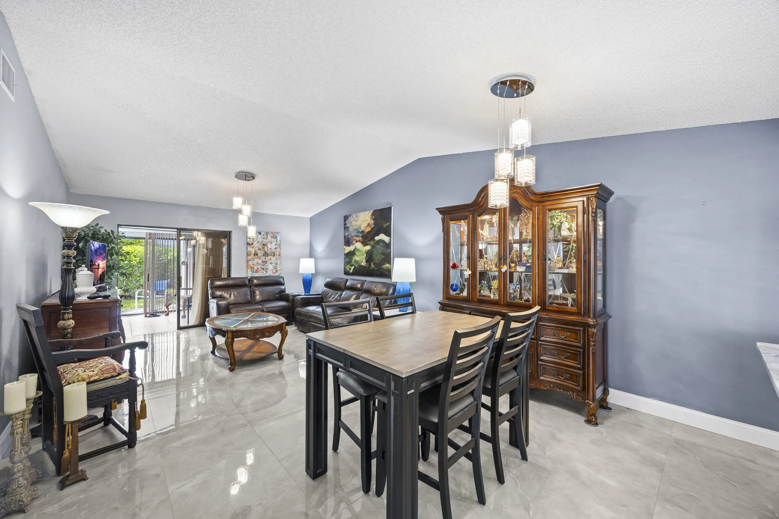 Bright, open-concept living and dining space with soaring ceilings and sleek tile flooring throughout, creating a spacious feel that’s perfect for both everyday living and entertaining.