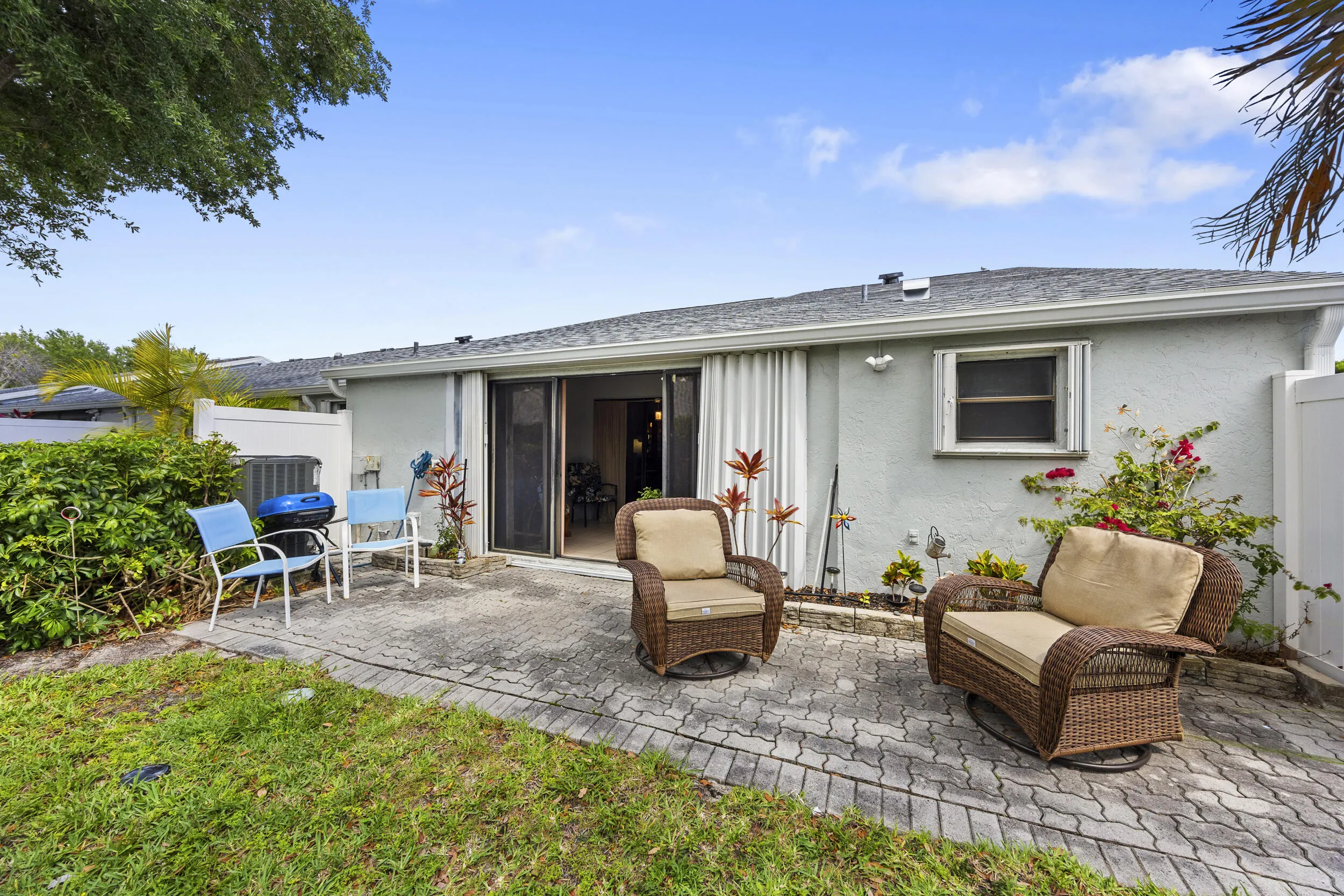 Charming outdoor patio space featuring a paver deck, perfect for relaxing or entertaining. Surrounded by lush tropical landscaping and privacy fencing, this inviting backyard offers a peaceful setting with plenty of room for outdoor seating, grilling, and enjoying the South Florida lifestyle.