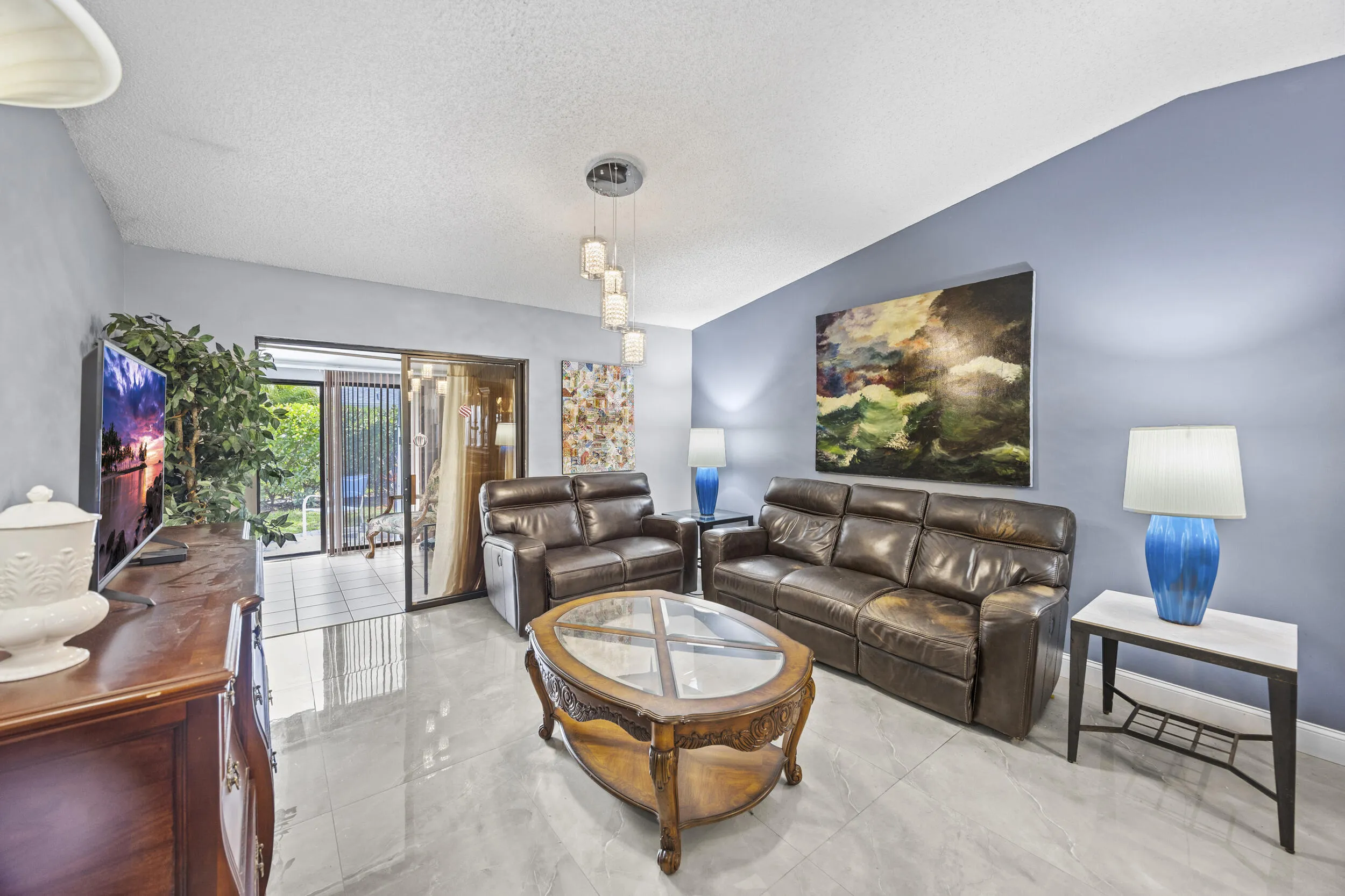 Bright and inviting living room with an open layout and seamless indoor-outdoor flow, featuring sleek tile flooring and sliding glass doors that lead to the private outdoor space—perfect for relaxing or entertaining.