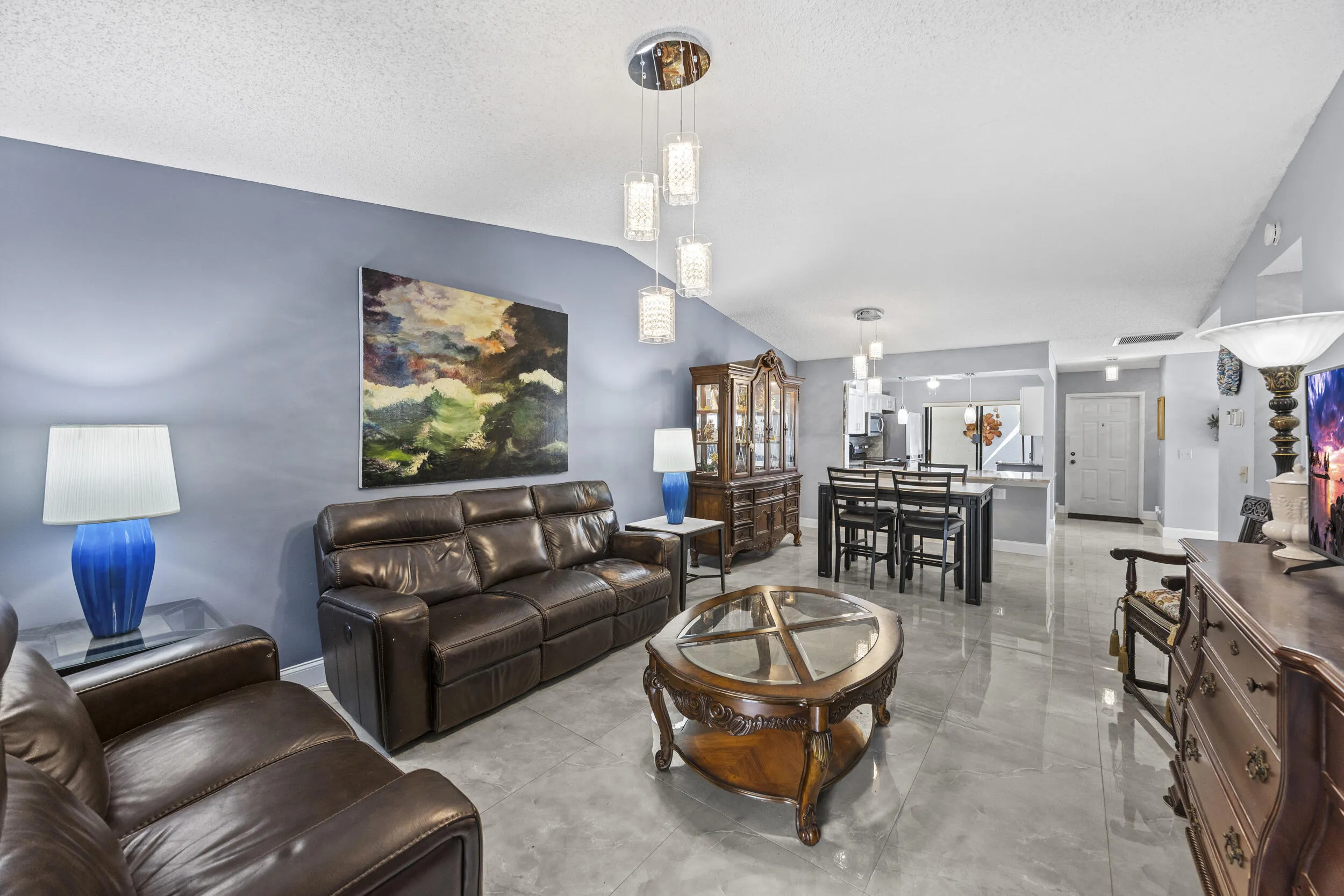 Bright and inviting living room with an open layout and seamless indoor-outdoor flow, featuring sleek tile flooring and sliding glass doors that lead to the private outdoor space—perfect for relaxing or entertaining.