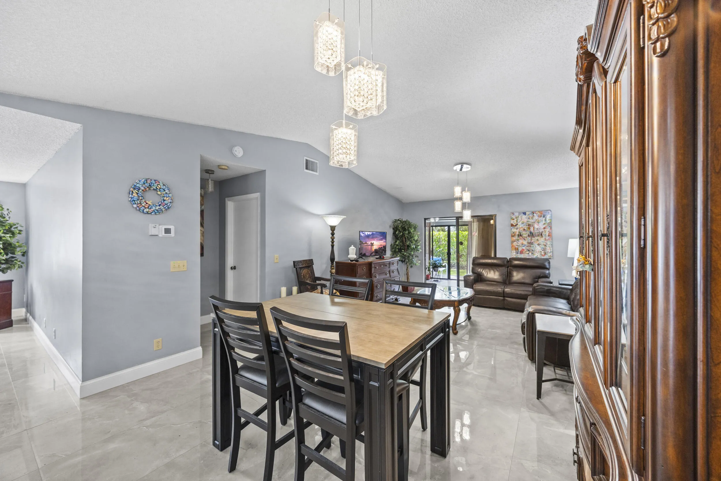 Bright, open-concept living and dining space with soaring ceilings and sleek tile flooring throughout, creating a spacious feel that’s perfect for both everyday living and entertaining.