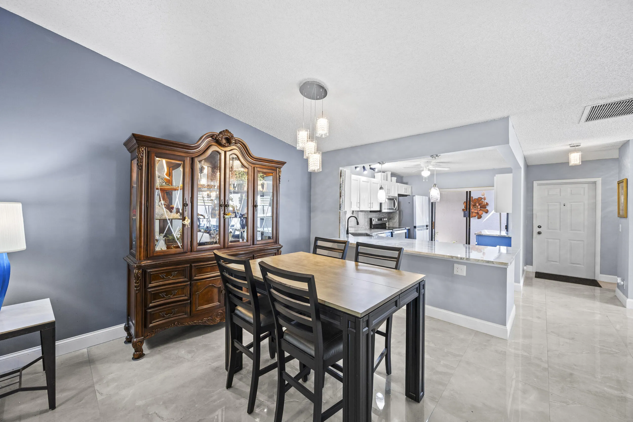 Bright, open-concept living and dining space with soaring ceilings and sleek tile flooring throughout, creating a spacious feel that’s perfect for both everyday living and entertaining.
