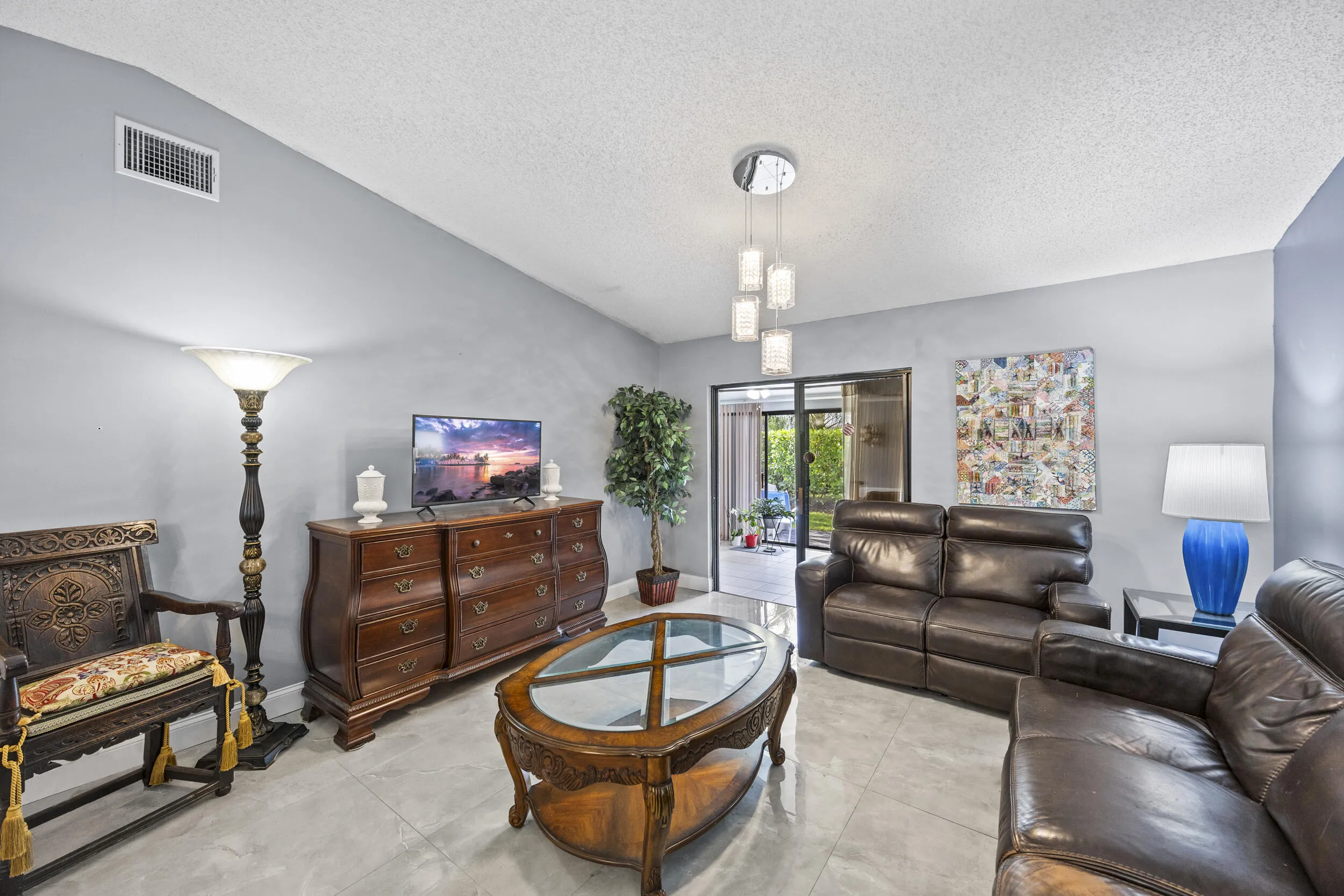 Bright and inviting living room with an open layout and seamless indoor-outdoor flow, featuring sleek tile flooring and sliding glass doors that lead to the private outdoor space—perfect for relaxing or entertaining.