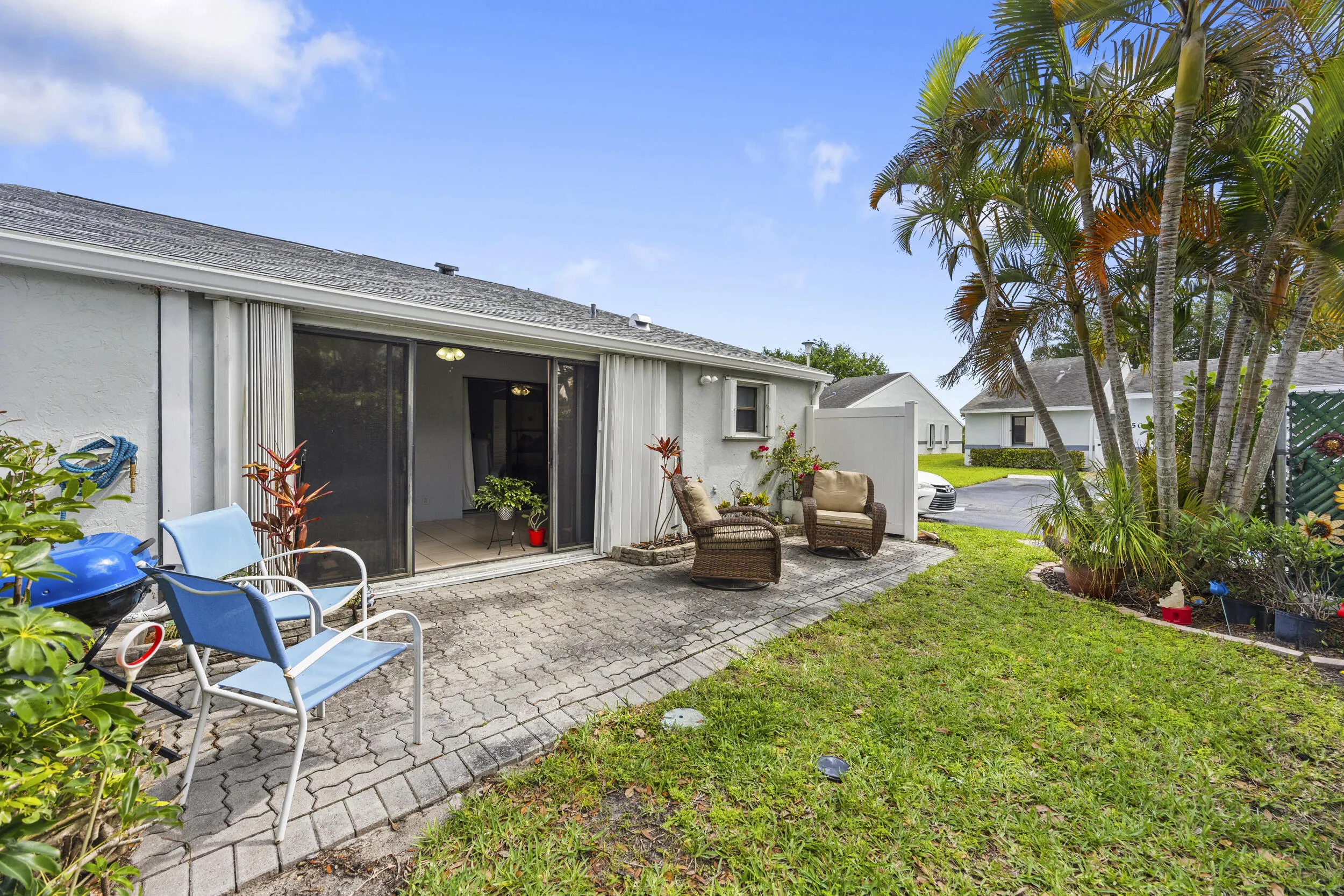 Charming outdoor patio space featuring a paver deck, perfect for relaxing or entertaining. Surrounded by lush tropical landscaping and privacy fencing, this inviting backyard offers a peaceful setting with plenty of room for outdoor seating, grilling, and enjoying the South Florida lifestyle.
