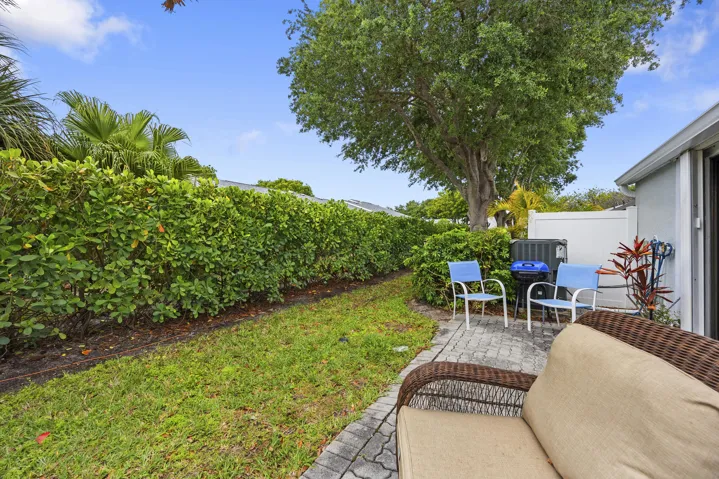 Charming outdoor patio space featuring a paver deck, perfect for relaxing or entertaining. Surrounded by lush tropical landscaping and privacy fencing, this inviting backyard offers a peaceful setting with plenty of room for outdoor seating, grilling, and enjoying the South Florida lifestyle.