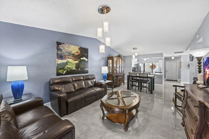 Bright and inviting living room with an open layout and seamless indoor-outdoor flow, featuring sleek tile flooring and sliding glass doors that lead to the private outdoor space—perfect for relaxing or entertaining.