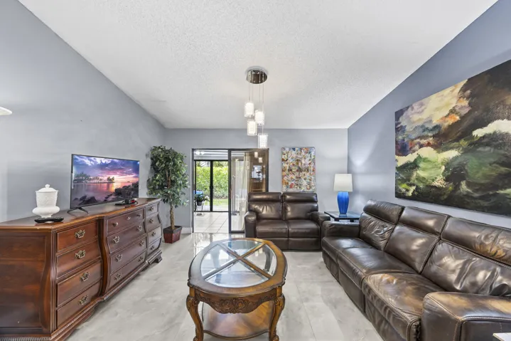 Bright and inviting living room with an open layout and seamless indoor-outdoor flow, featuring sleek tile flooring and sliding glass doors that lead to the private outdoor space—perfect for relaxing or entertaining.