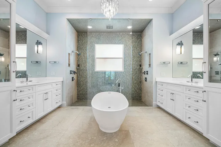 Spa like primary bathroom with separate vanities, dual shower heads and a rainfall shower.