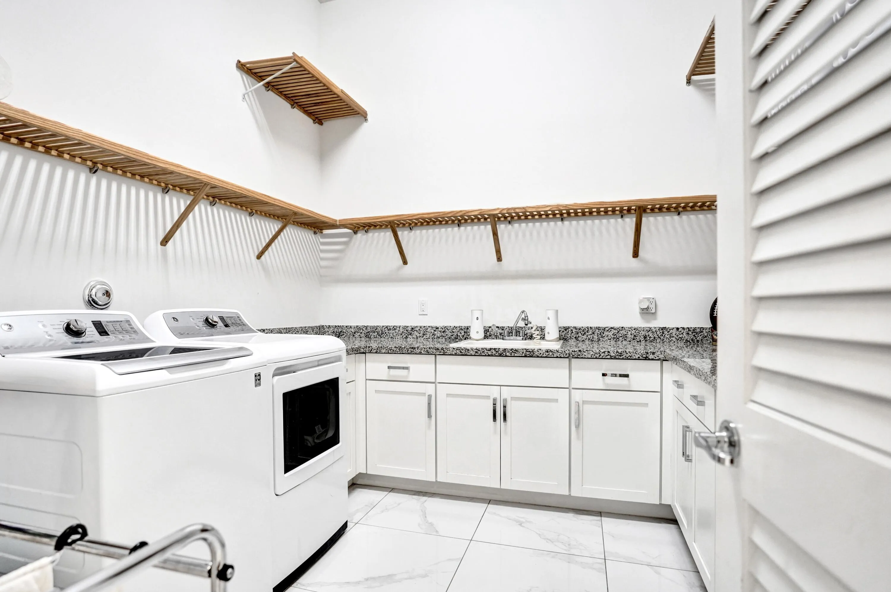 Large laundry with gas dryer, shelving, storage and sink on first floor.