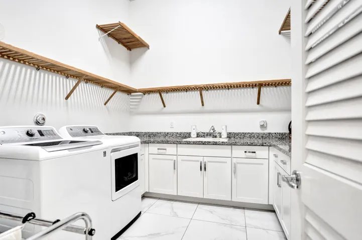 Large laundry with gas dryer, shelving, storage and sink on first floor.