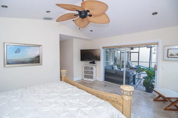 MASTER BEDROOM WITH SLIDING GLASS DOORS LOOKING OUT TO POOL/SCREENED IN PATIO AREA