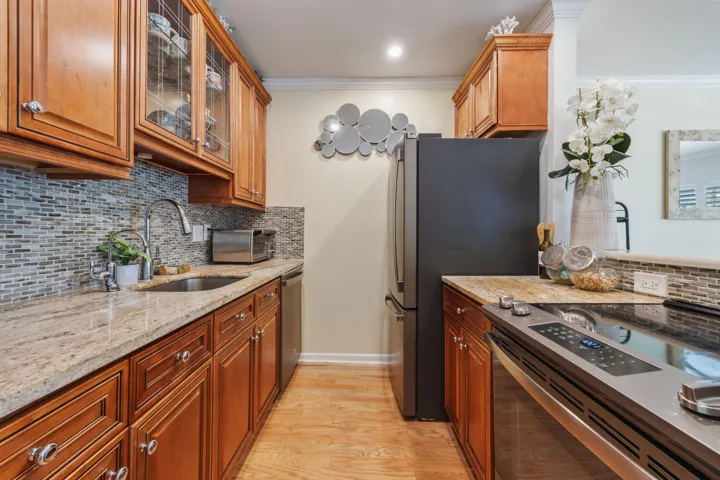 Open kitchen, with granite countertops, glasstile backsplash, updated appliances & raised wood panel cabinetry