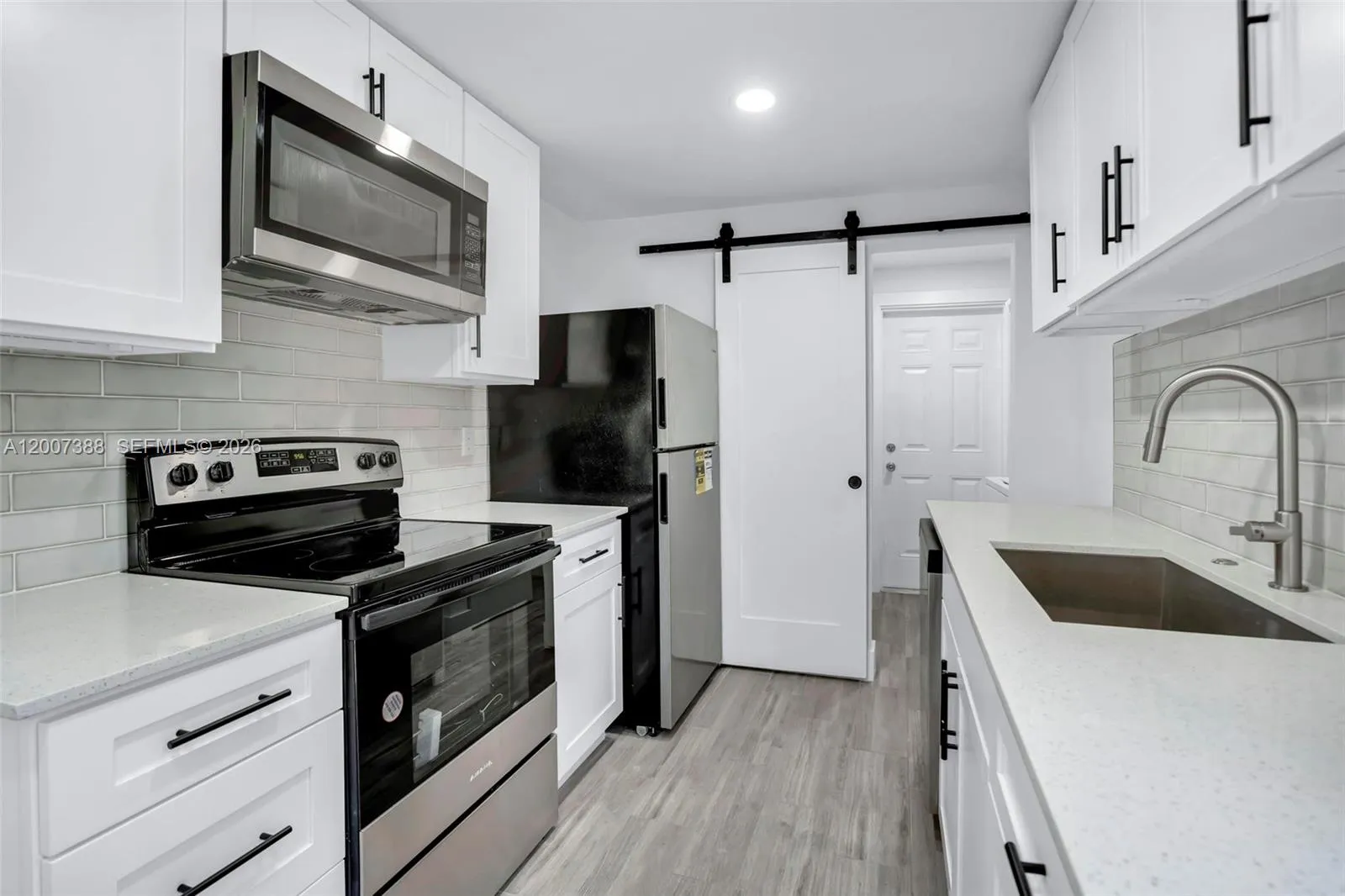 Kitchen leading into storage and laundry
