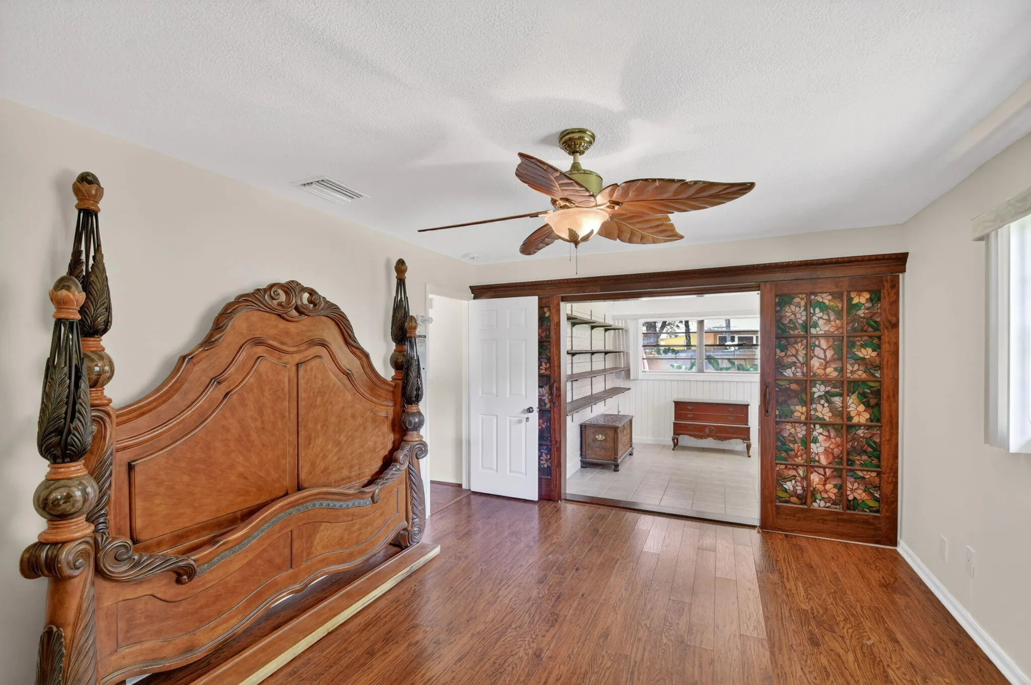 Primary bedroom boasts wood laminate flooring, fresh paint and a bonus room behind the wood doors