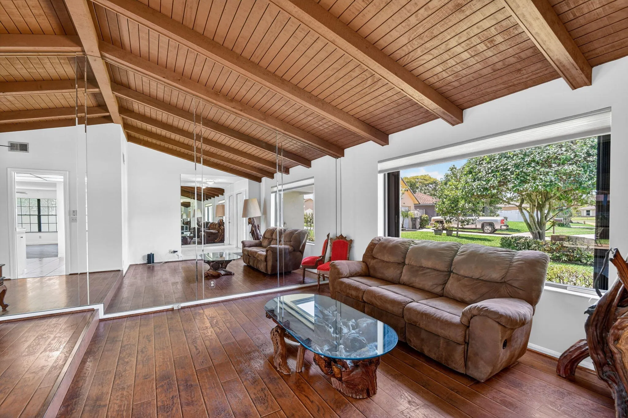 Living room boasts picture wood, cathedral ceiling accented with wood beams and wood laminate floor.