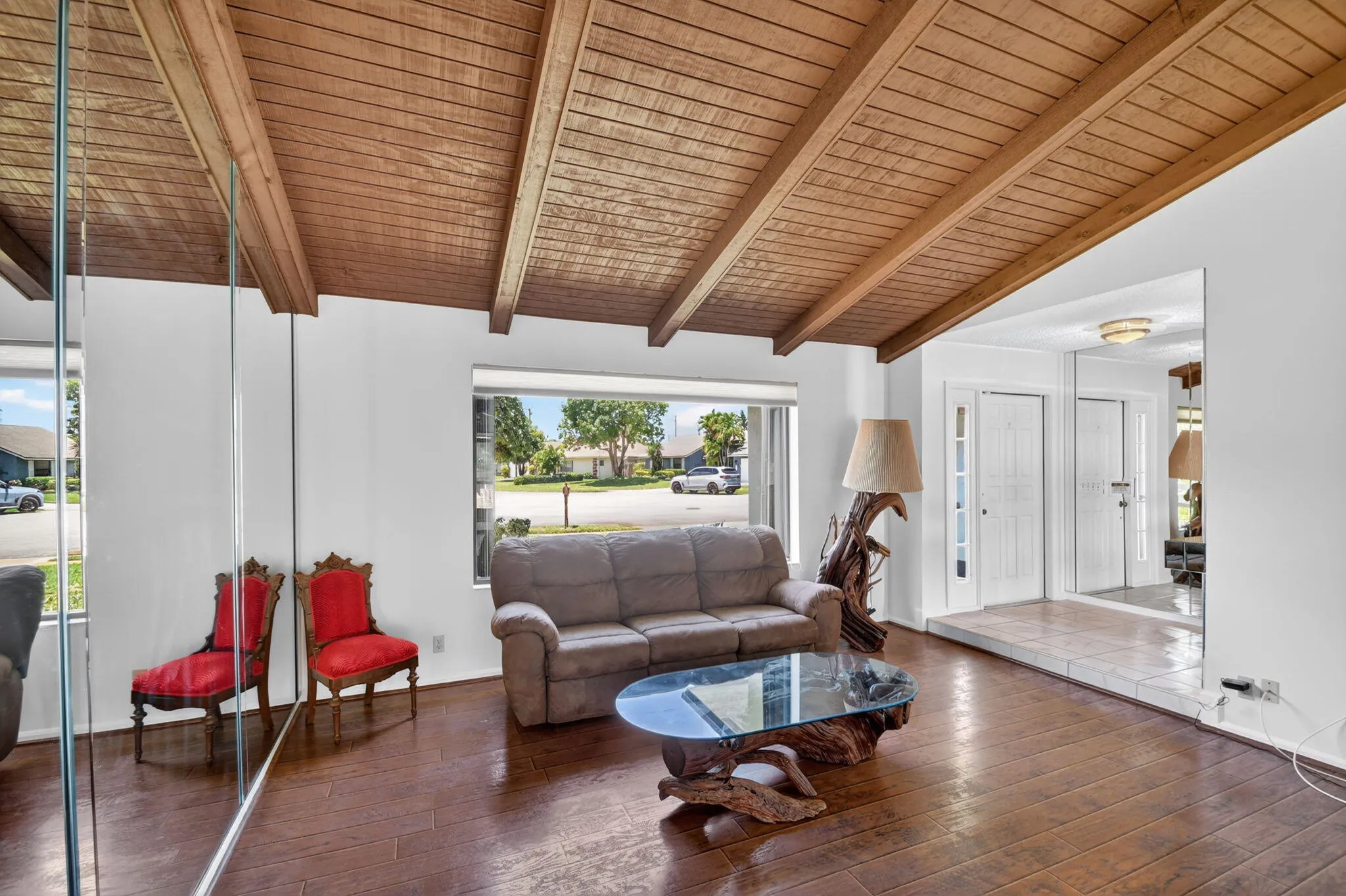 Living room boasts picture wood, cathedral ceiling accented with wood beams and wood laminate floor.