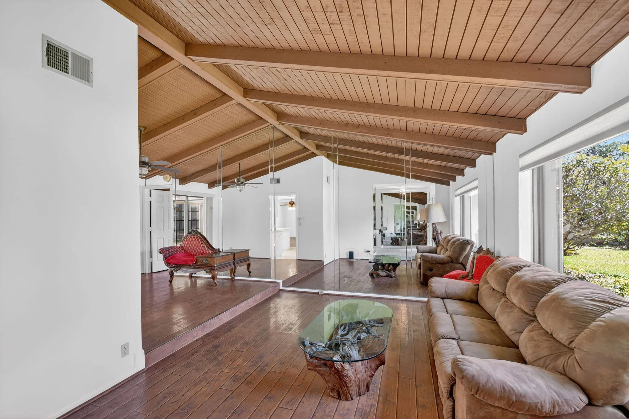 Living room boasts picture wood, cathedral ceiling accented with wood beams and wood laminate floor.