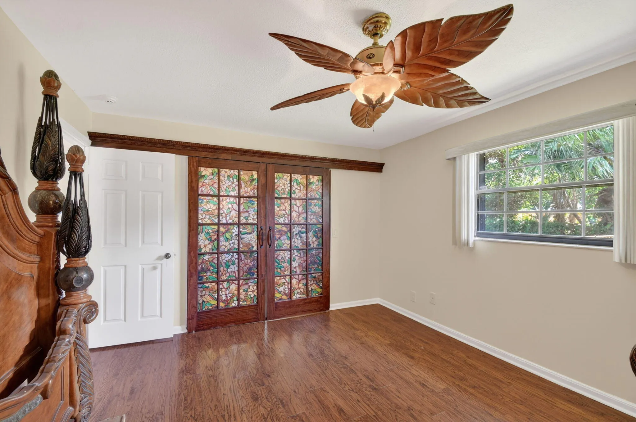 Primary bedroom boasts wood laminate flooring, fresh paint and a bonus room behind the wood doors