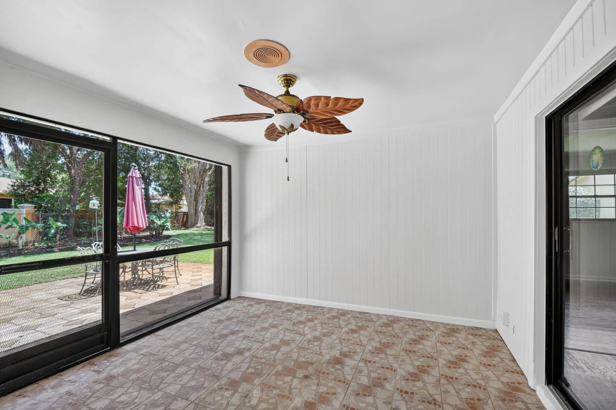 Covered patio leads to extended paver patio and expansive back yard